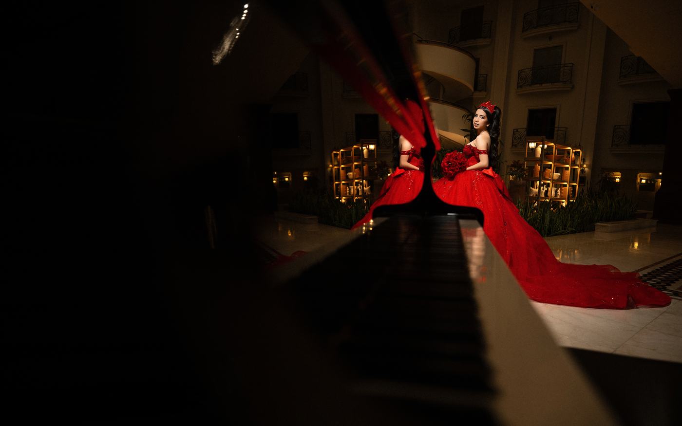 Quinceañera con vestido rojo reflejada en un piano